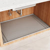 A silicone under sink waterproof mat is installed in a wooden cabinet below a white countertop.