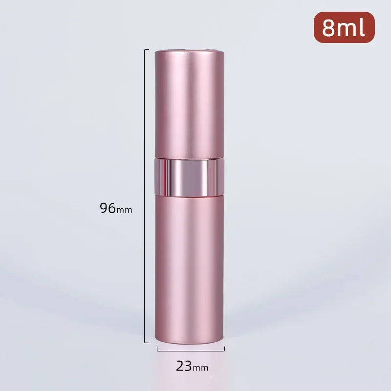 A tall, cylindrical pink perfume spray bottle with a silver cap and a black label, shown against a light gray background.