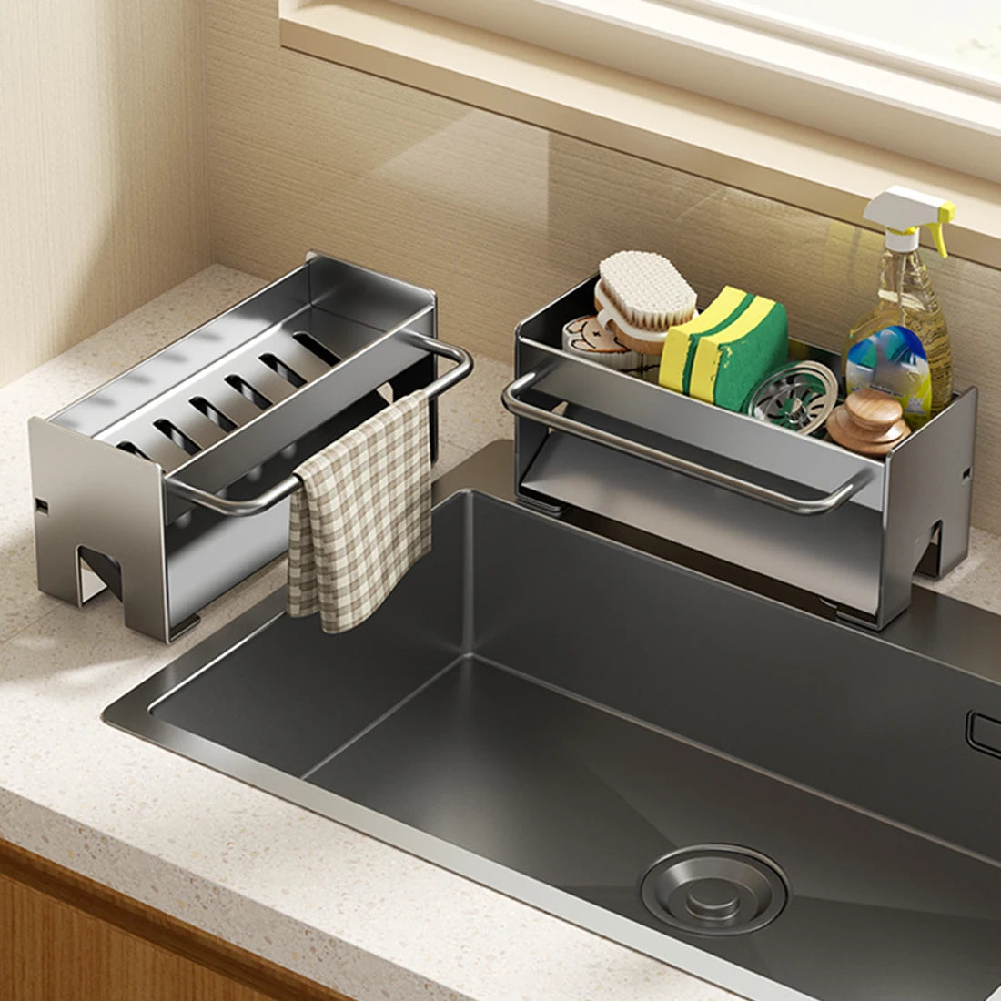 A stainless steel kitchen sink caddy with a draining tray for holding sponges and dish tools is shown next to a sink.