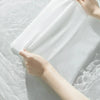A hand is gently pressing a white disposable compressed washcloth onto the surface of water.