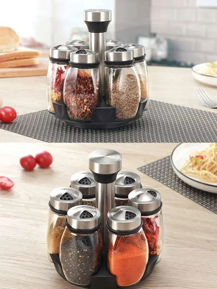A set of rotating glass spice jars with stainless steel lids arranged on a black stand.
