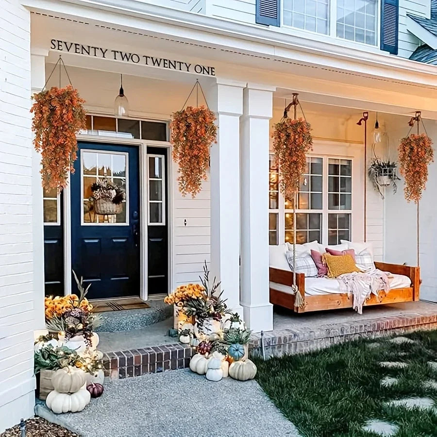 An entryway featuring a white door and porch decorated with artificial flower garlands and potted plants.
