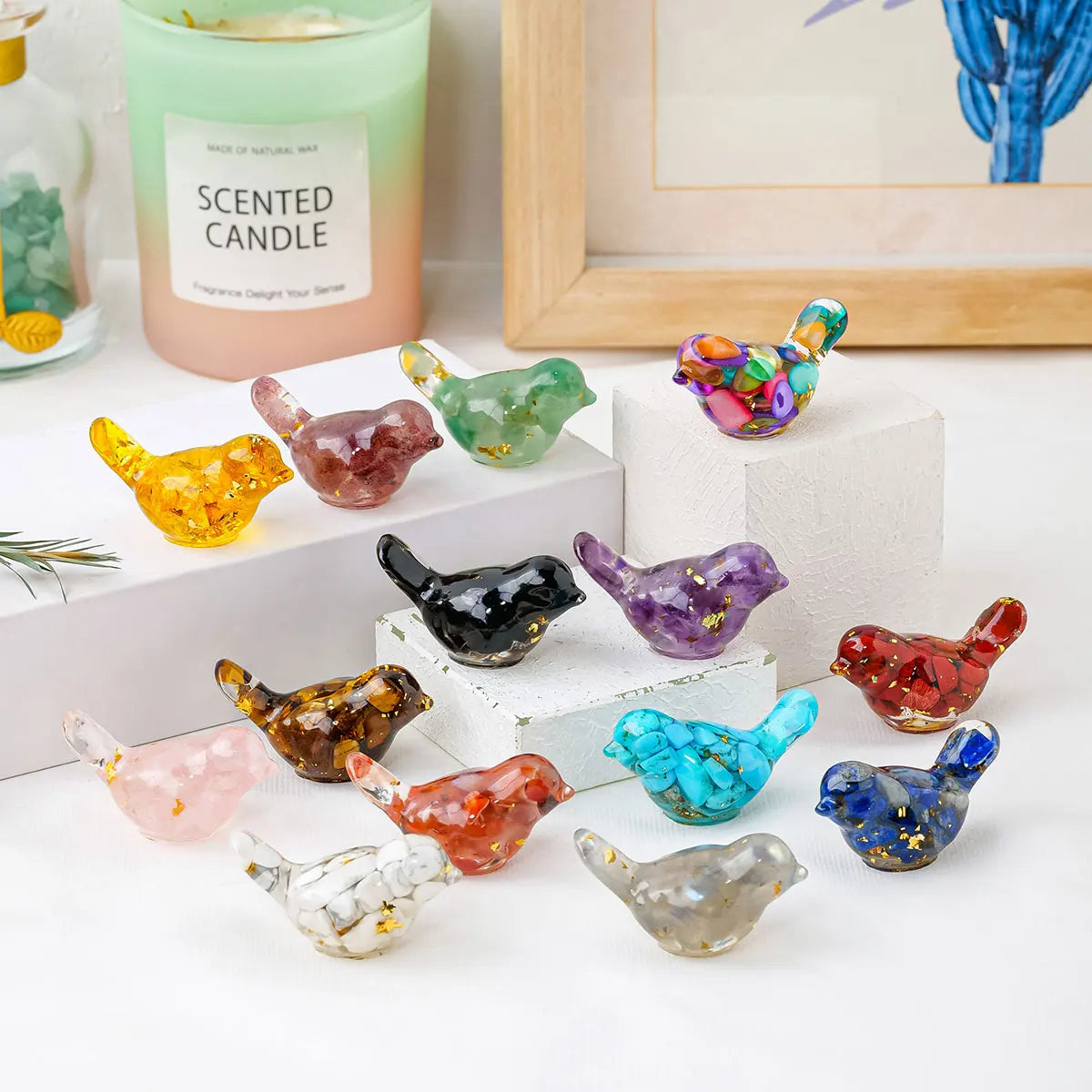 A collection of colorful crystal bird statues in various shades of green, purple, orange, and yellow displayed on a white sur