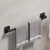 A black wall-mounted towel rack holding a gray striped towel on a light gray wall.