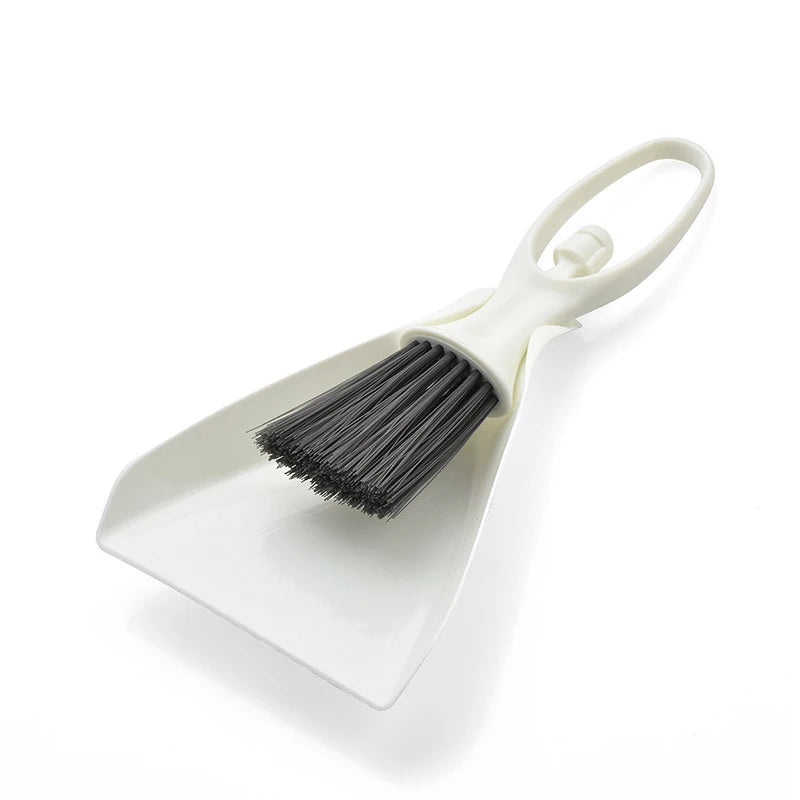 A white mini broom and dustpan set with a handle and bristles for cleaning desks and keyboards.
