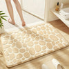 A beige pebble embossed bathroom rug placed on a wooden floor next to a white radiator.