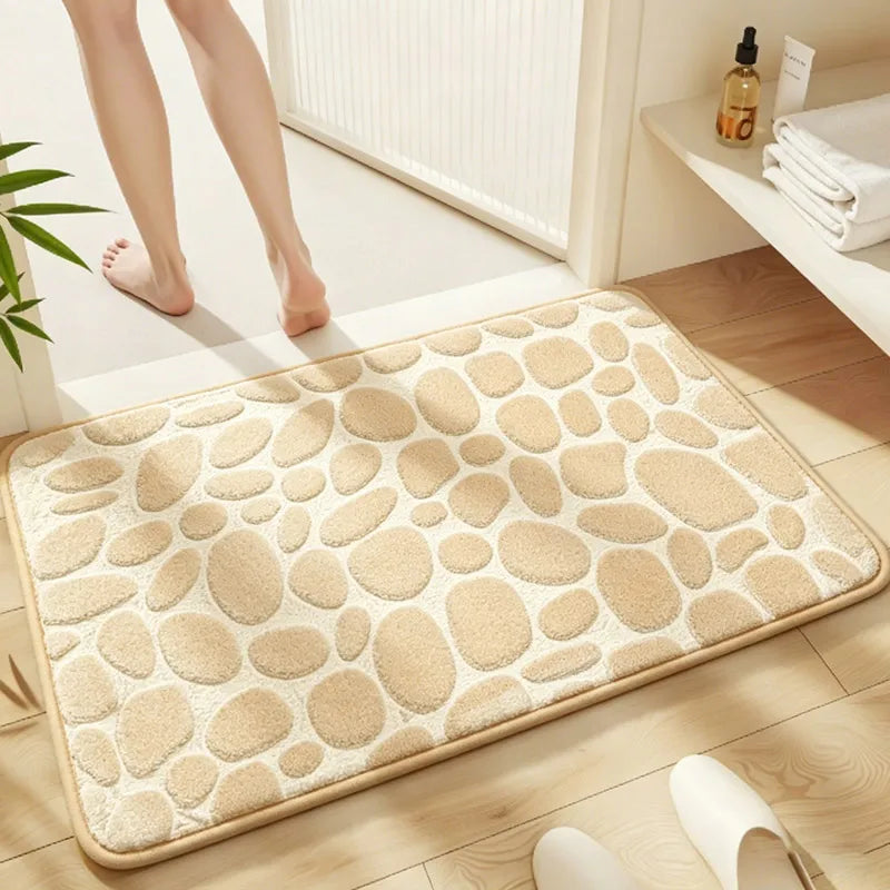 A beige pebble embossed bathroom rug placed on a wooden floor next to a white radiator.
