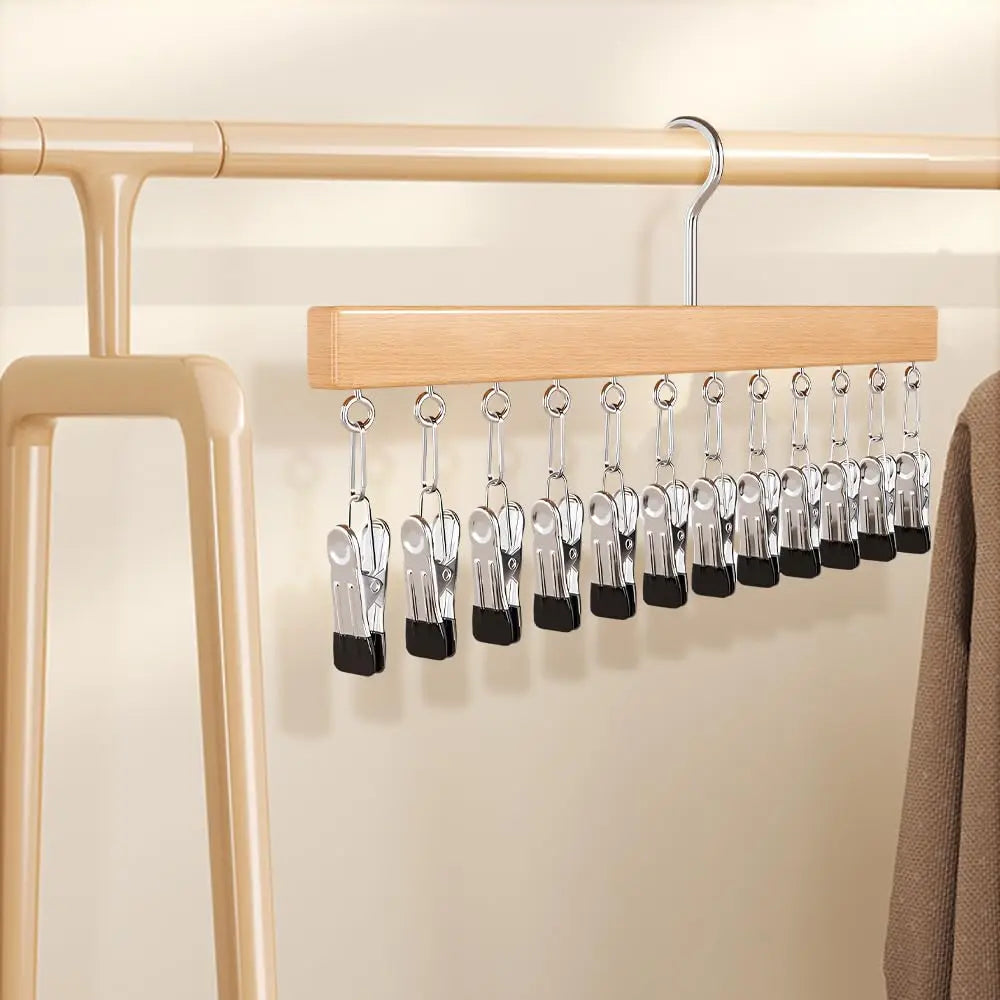Ein hölzerner Kleiderbügel mit mehreren Metallclips wird an einer hellen Wand ausgestellt.