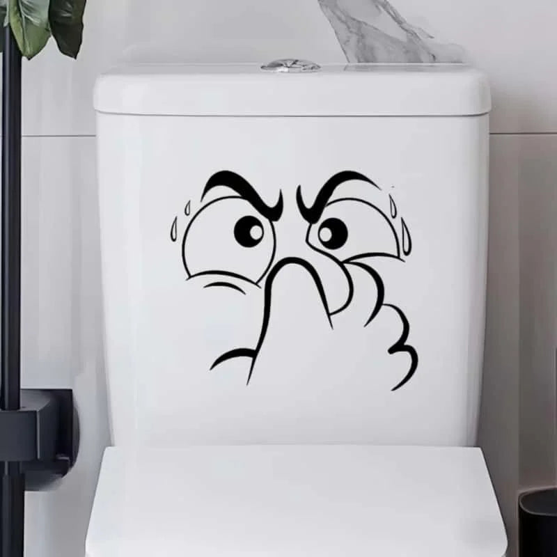 A white toilet lid featuring a black cartoon drawing of an angry, squinting face with tears.