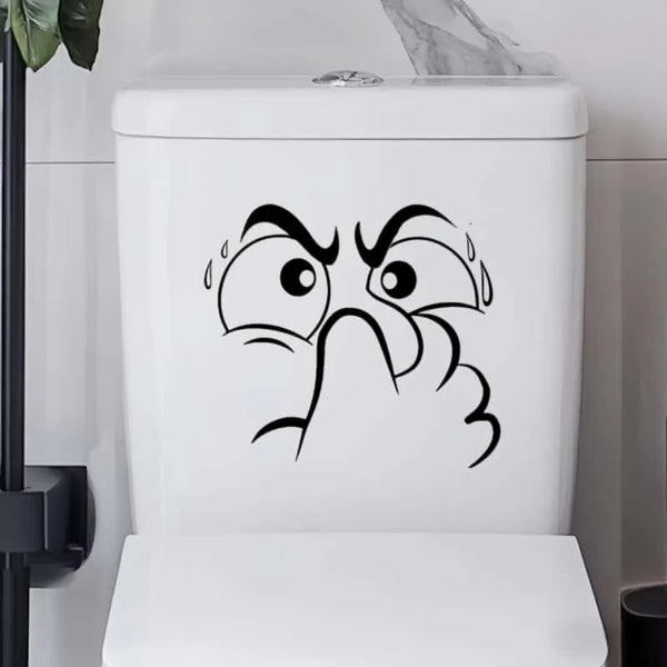 A white toilet lid featuring a black cartoon drawing of an angry, squinting face with tears.