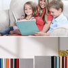 Eine Familie liest gemeinsam ein Leinen-Fotobuch mit Klebefolien auf einem Sofa.