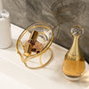 A gold leaf soap dish with a glass bowl and a golden soap dispenser sitting on a white countertop.