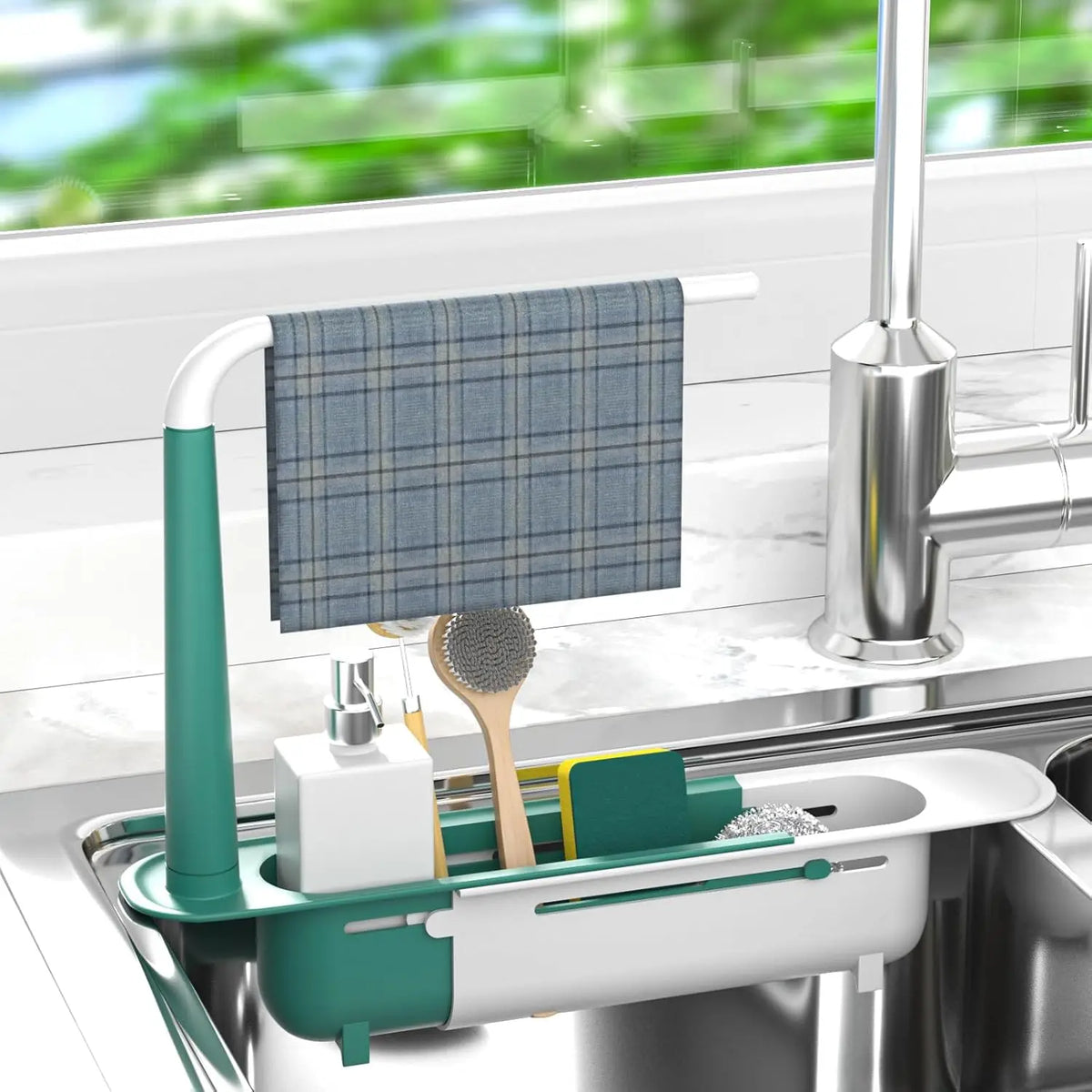 A white and teal adjustable over-sink dish rack organizer holding a blue plaid dishcloth and a brush.