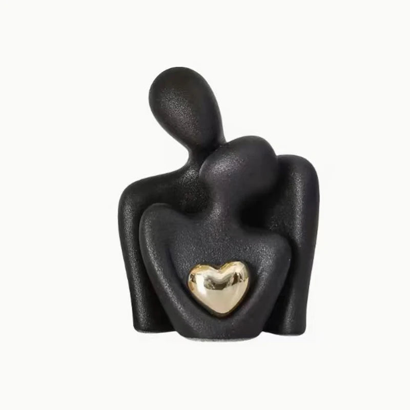 Eine schwarze, abstrakte Statue, die zwei sich umarmende Figuren darstellt.