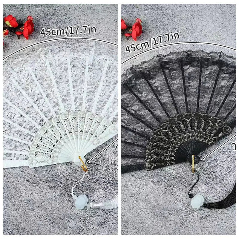 A white lace fabric folding hand fan with a black and gray design shown next to a red rose.
