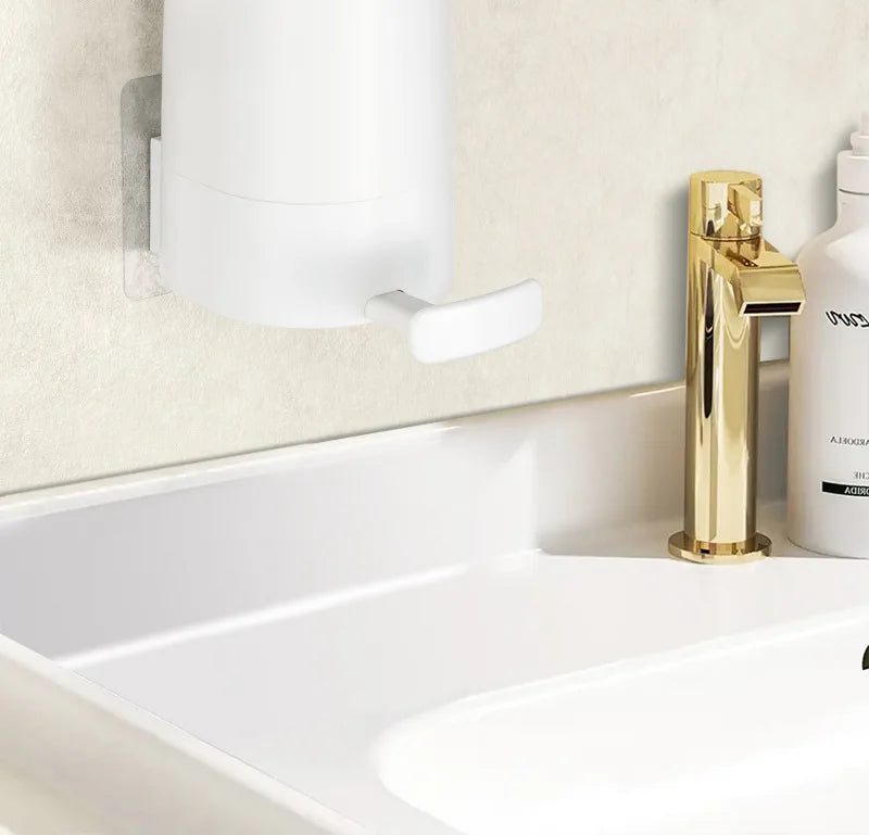 A white portable soap bar grinder with a wall-mount design next to a gold faucet on a bathroom sink.