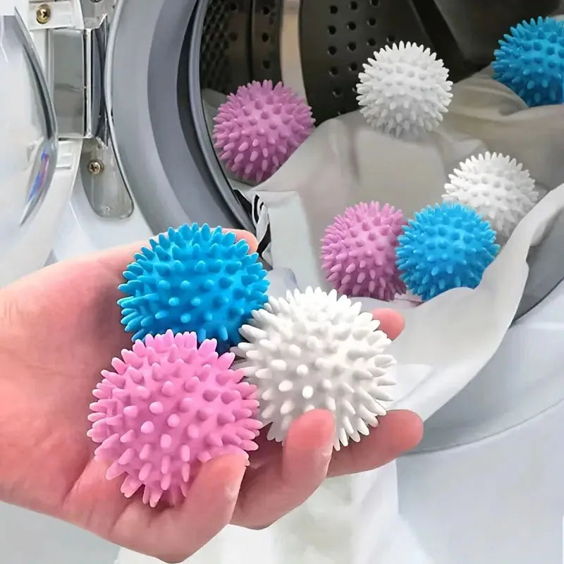 A hand holds several reusable laundry balls in various colors including blue, pink, and white.