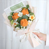 A bouquet of handmade sunflowers crochet flowers in orange and white with green leaves and a paper tag.