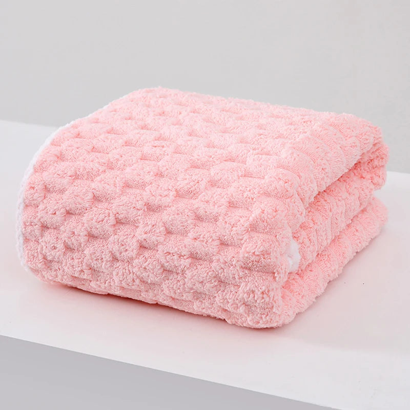 A thick pink microfiber bath towel folded on a white surface.