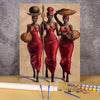Two women in red dresses hold woven hats and spears against a light background.