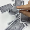 A hand is holding and examining a stack of black and white patterned poker playing cards.