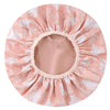 A pink floral patterned reusable satin lined shower cap.