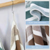 A white and brown striped bath towel hanging on a wooden rack, demonstrating tight edge wrapping and skin friendly features.