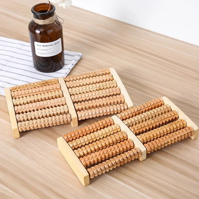 Ein Set hölzerner Fußmassiererollen mit mehreren Steuerungspunkten auf einem hellen Holzbrett.