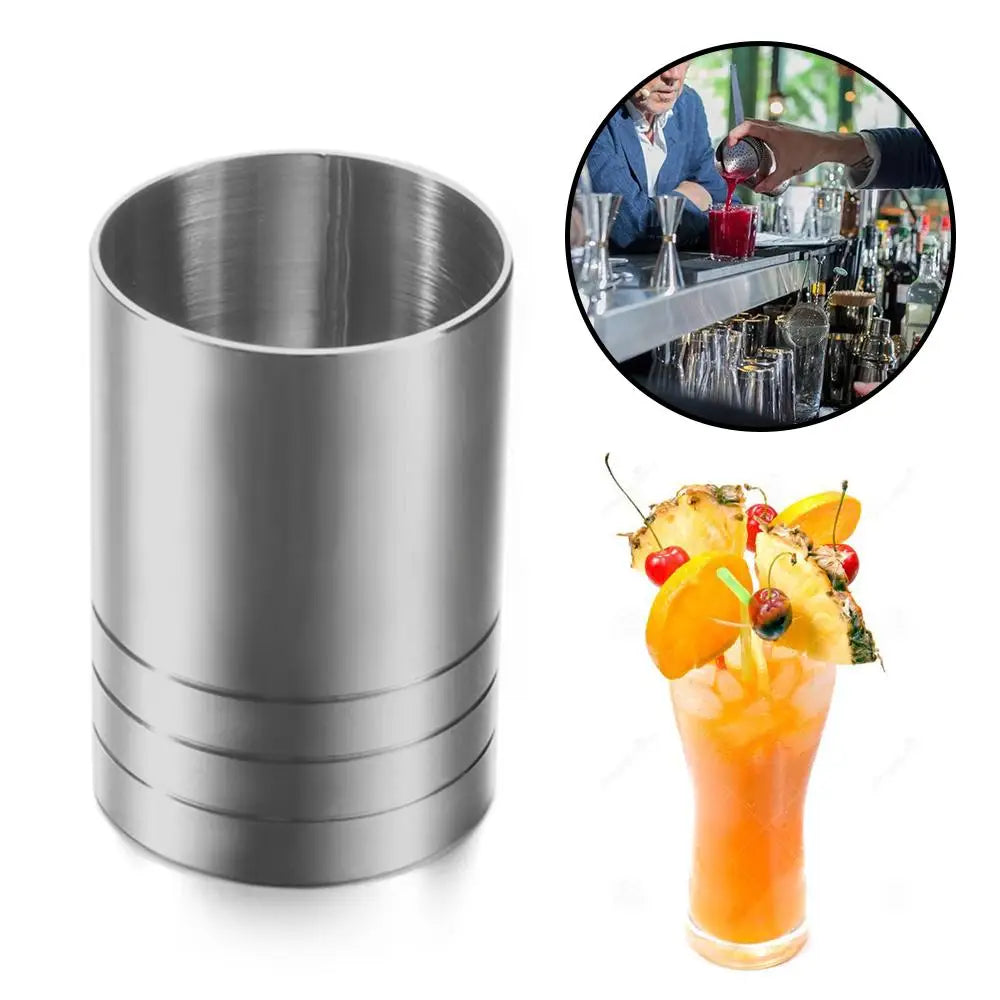 A stainless steel bar measure is shown next to a cocktail in a glass.