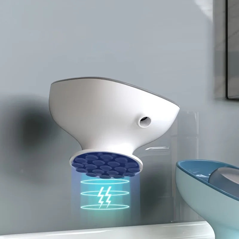 A white leaf-shaped bathroom soap dish drainer mounted on a wall, with blue light illuminating the drain area.