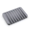 A gray self-draining silicone soap dish with an anti-slip base.