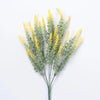 Sprigs of artificial yellow lavender flowers with green foliage.