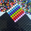 A close-up of colorful round building blocks arranged in a diamond pattern on a black surface.
