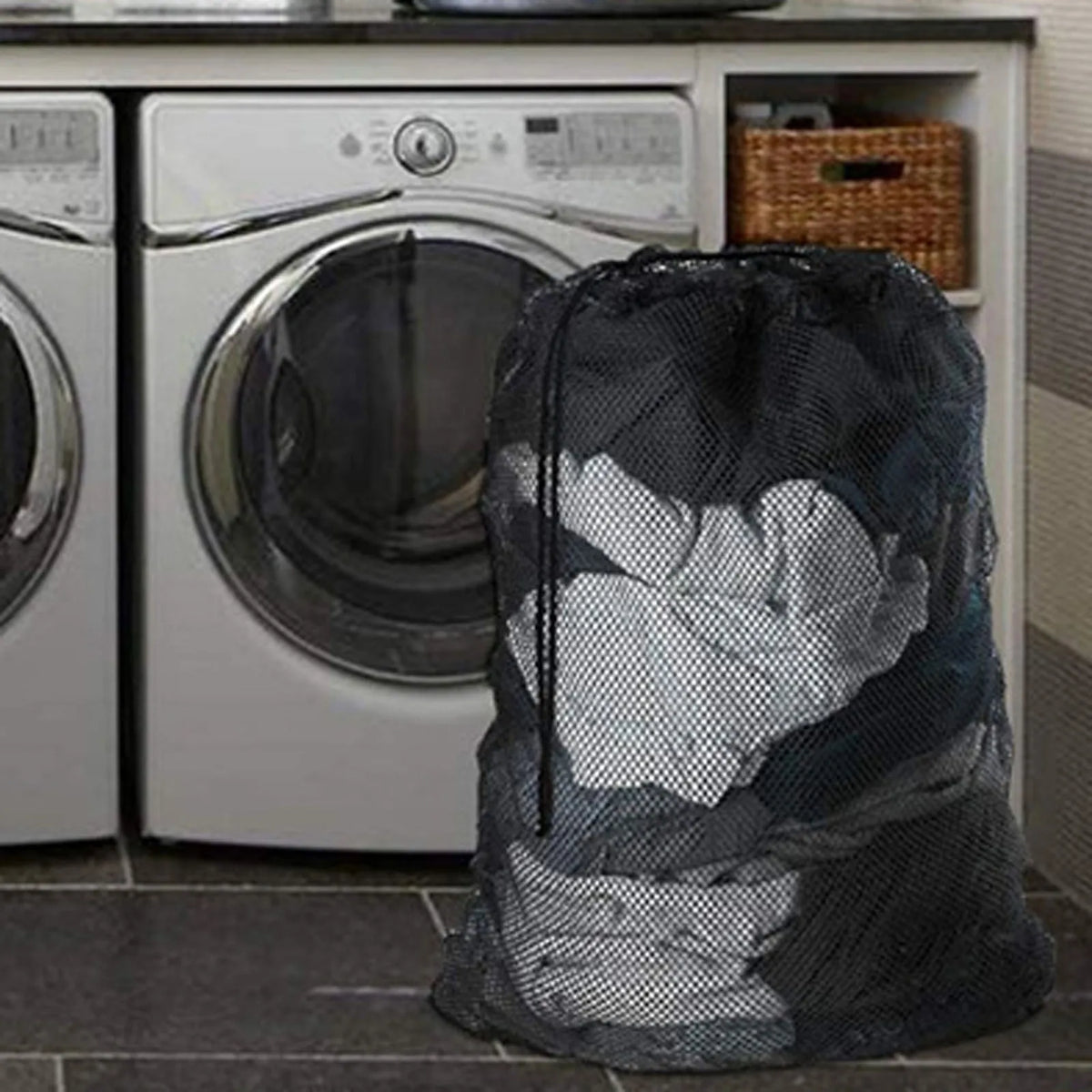 Eine große schwarze Netzwaschtasche gefüllt mit Kleidung steht auf einer Küchenarbeitsplatte neben einer Waschmaschine.
