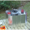 A shiny stainless steel multi-plate outdoor gas stove wind shield placed on a wooden table with fresh fruit.