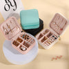 A pink portable PU leather jewelry storage box with a teal fabric pouch and various gold and silver jewelry items.