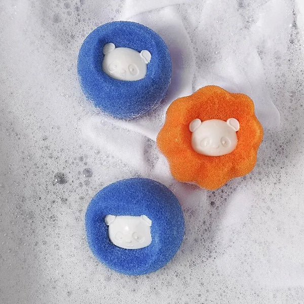 Two blue and orange laundry balls with white bear shapes are shown in soapy water.