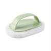 A light green magic sponge scrubber with an ergonomic handle resting on a white foam pad.