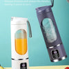 Extractor de jugo eléctrico portátil morado con mango de silicona junto a frutas frescas.
