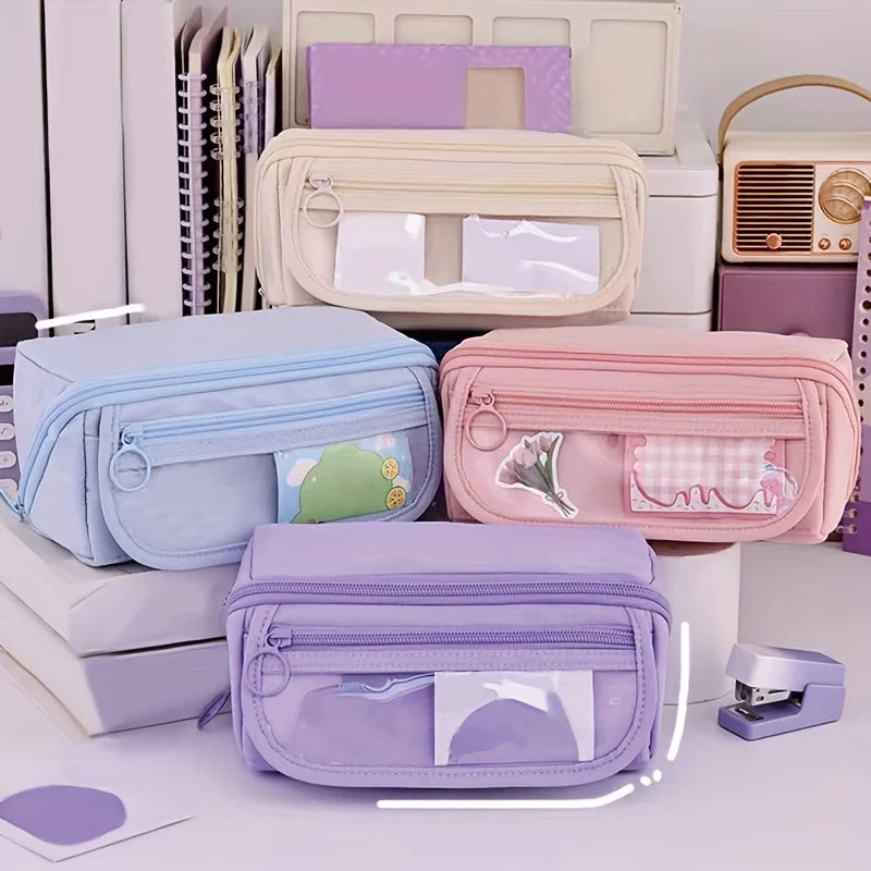 A collection of multi-compartment pencil cases and organizers in pastel colors like lavender, pink, and blue are displayed on