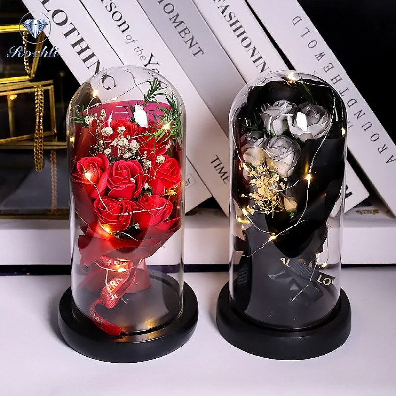 Glasvase mit roten Rosen und LED-Lichtern auf schwarzem Sockel