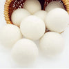 A basket filled with white reusable wool dryer balls for clothes drying.