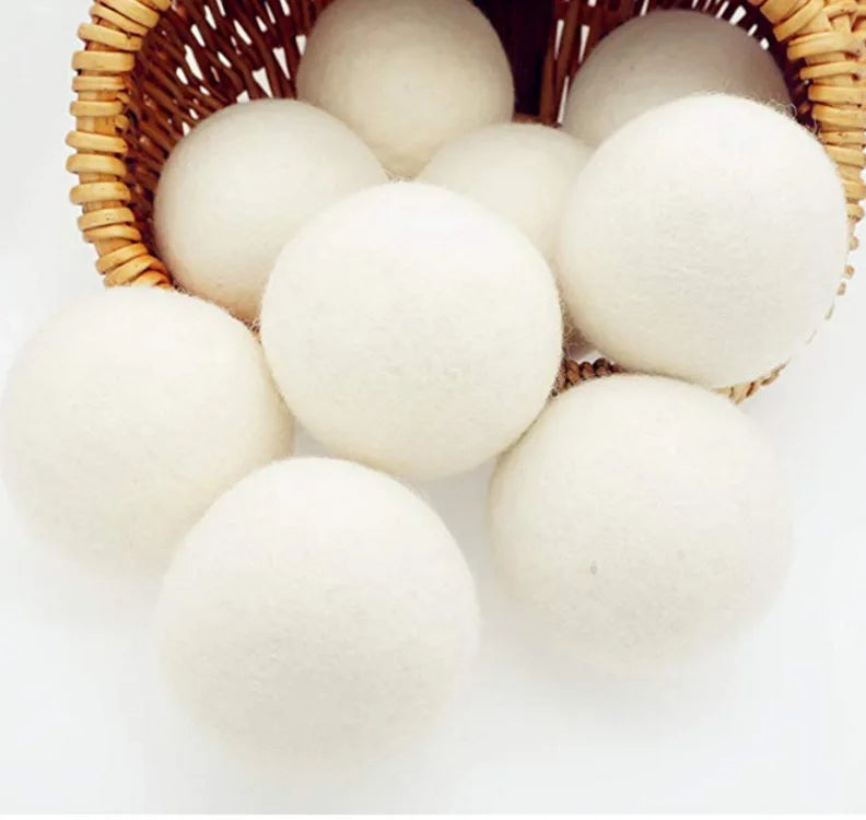 A basket filled with white reusable wool dryer balls for clothes drying.