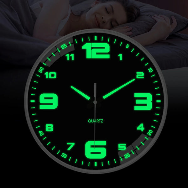 A glowing green quartz analog clock face is shown resting on a dark surface next to a person sleeping.