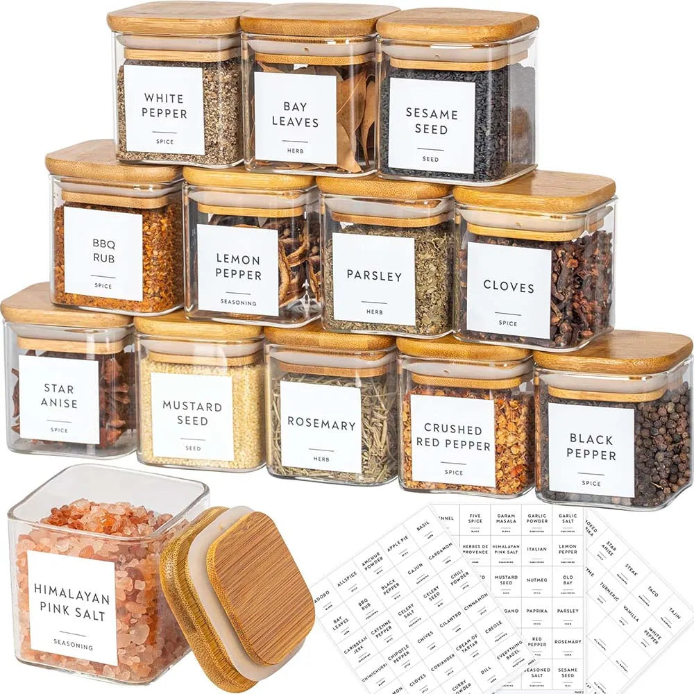 A collection of glass spice jars with bamboo lids containing various ground spices and herbs.