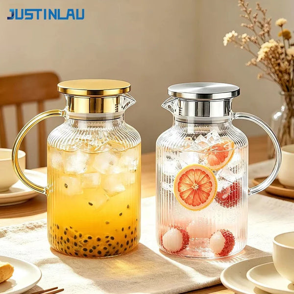 A clear glass pitcher filled with iced tea and fruit, featuring a gold-colored lid and handle.