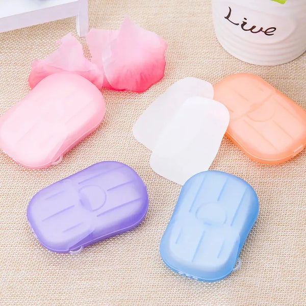 A collection of pink, white, and orange portable soap flakes for hand cleaning displayed on a beige fabric.