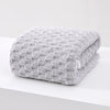 A thick, gray microfiber bath towel folded neatly on a white surface.