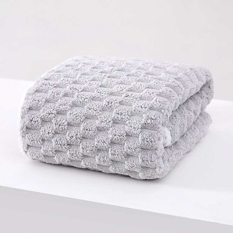 A thick, gray microfiber bath towel folded neatly on a white surface.