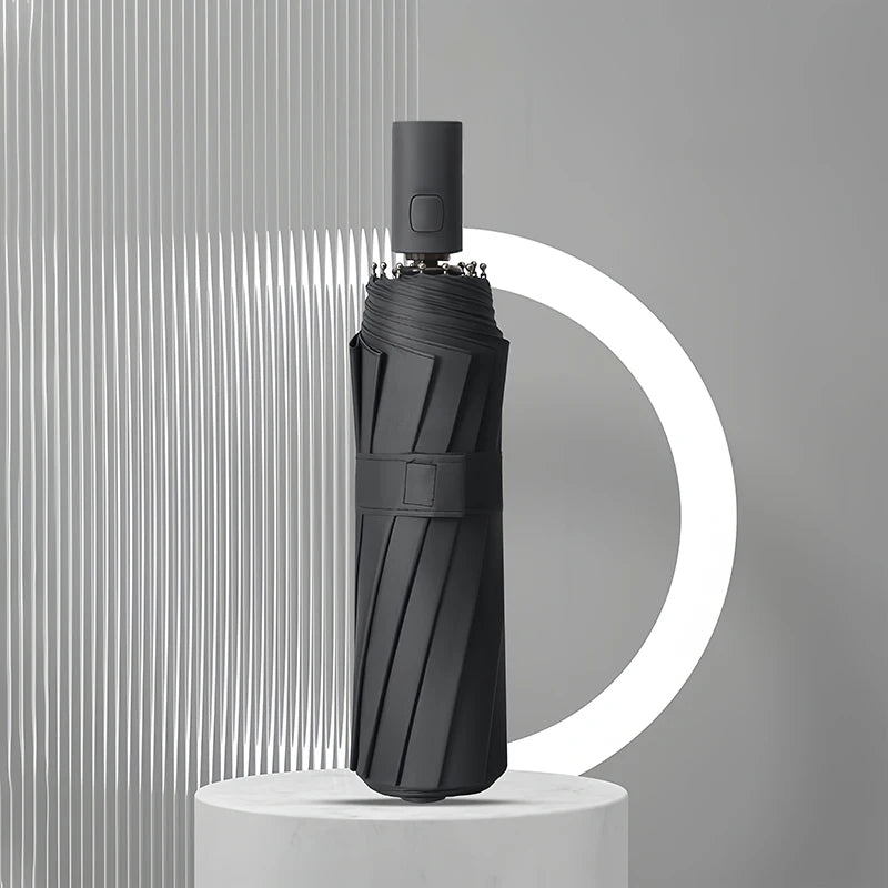 A black heavy duty automatic windproof umbrella standing upright against a light gray background.